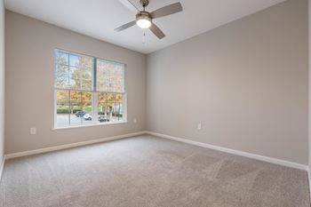 an empty room with a large window and a ceiling fan at The Enclave at Crossroads, North Carolina